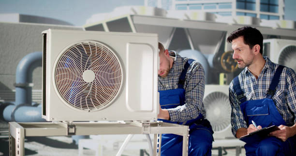 A man diligently cleaning an air conditioning unit in Deerfield Beach, ensuring efficient operation in a bright indoor space.