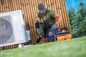 A man is engaged in fixing an AC unit, inspecting its mechanical elements.