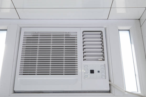 A white sliding window AC installed in a room with white tiled flooring.