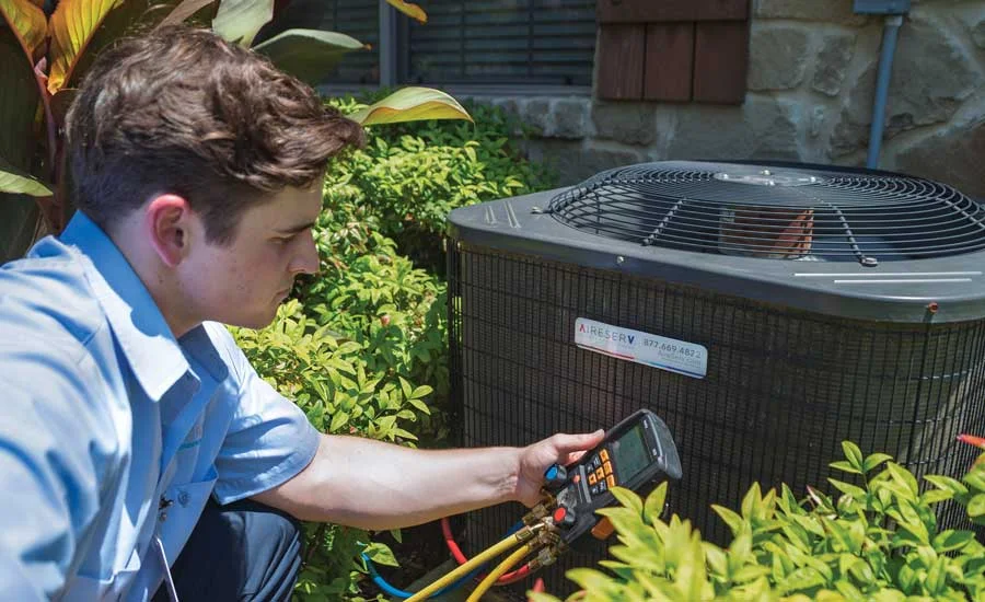 HVAC technician removing old air conditioner condenser outdoors
