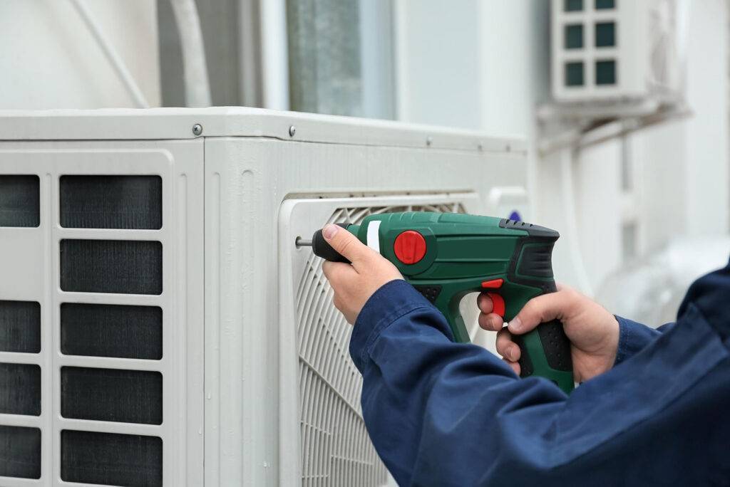 Technician performing air conditioner repair using tools indoors