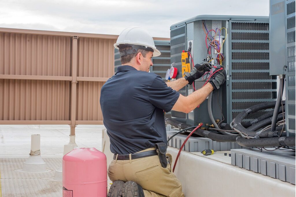 Air conditioner unit technician a Daylight AC units on building rooftop