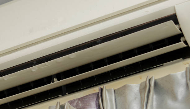 A room featuring an air conditioner with curtains, clearly showing signs of AC leaking water inside, leading to potential water damage.