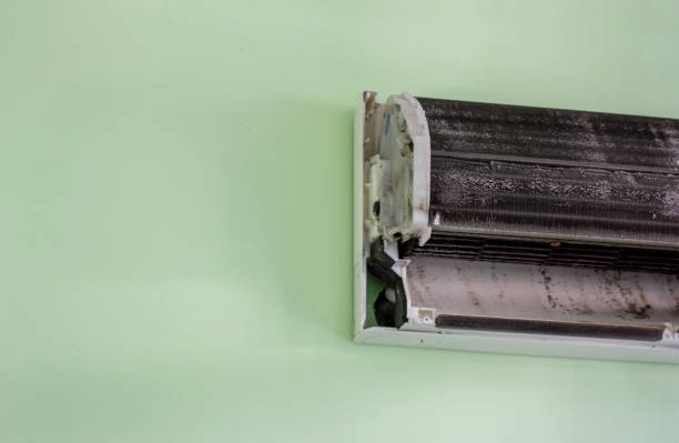 Air conditioner in a room with curtains, showing water leaking from the unit onto the floor — a clear case of AC leaking water inside.