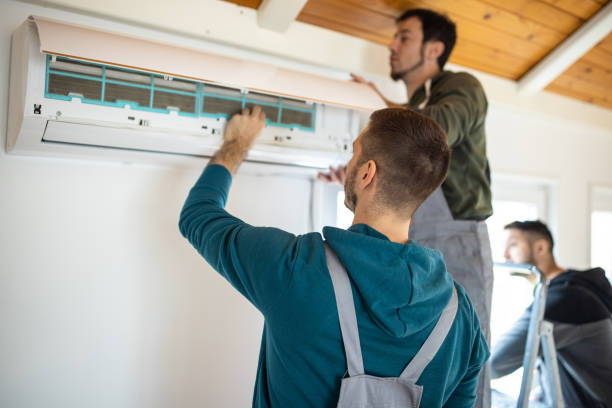 Two men repairing an air conditioner in a residential setting, focused on their work — a typical scene when searching for AC repair close to me.