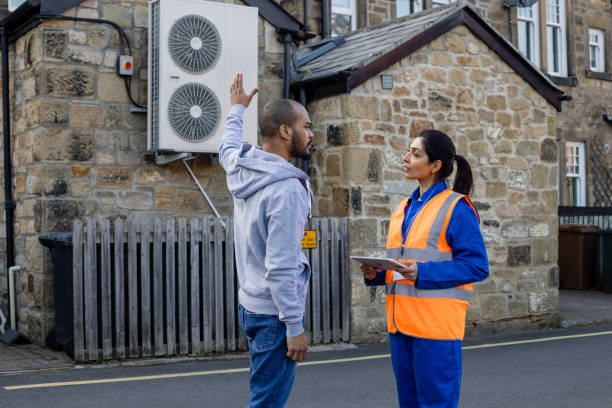 A person wearing blue overalls holds a gauge on an air conditioner, showcasing Reliable Air Conditioning Brand.