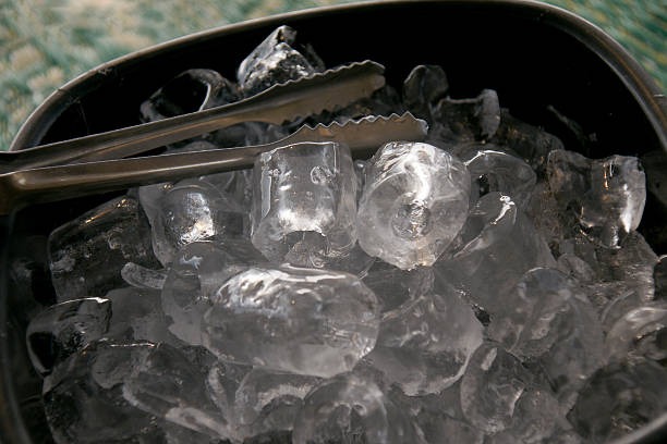 A black bucket filled with ice, positioned to the side, with warm air blowing around it.