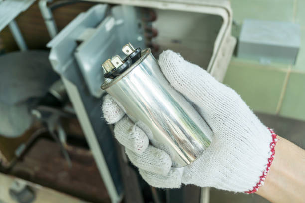 A person holding a metal canister labeled as a blown AC capacitor in their hand.